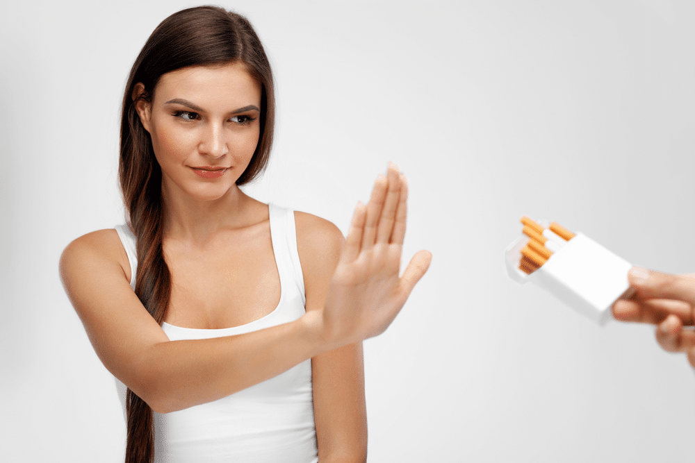 A girl with a white top says, "Stop smoking," with her hand